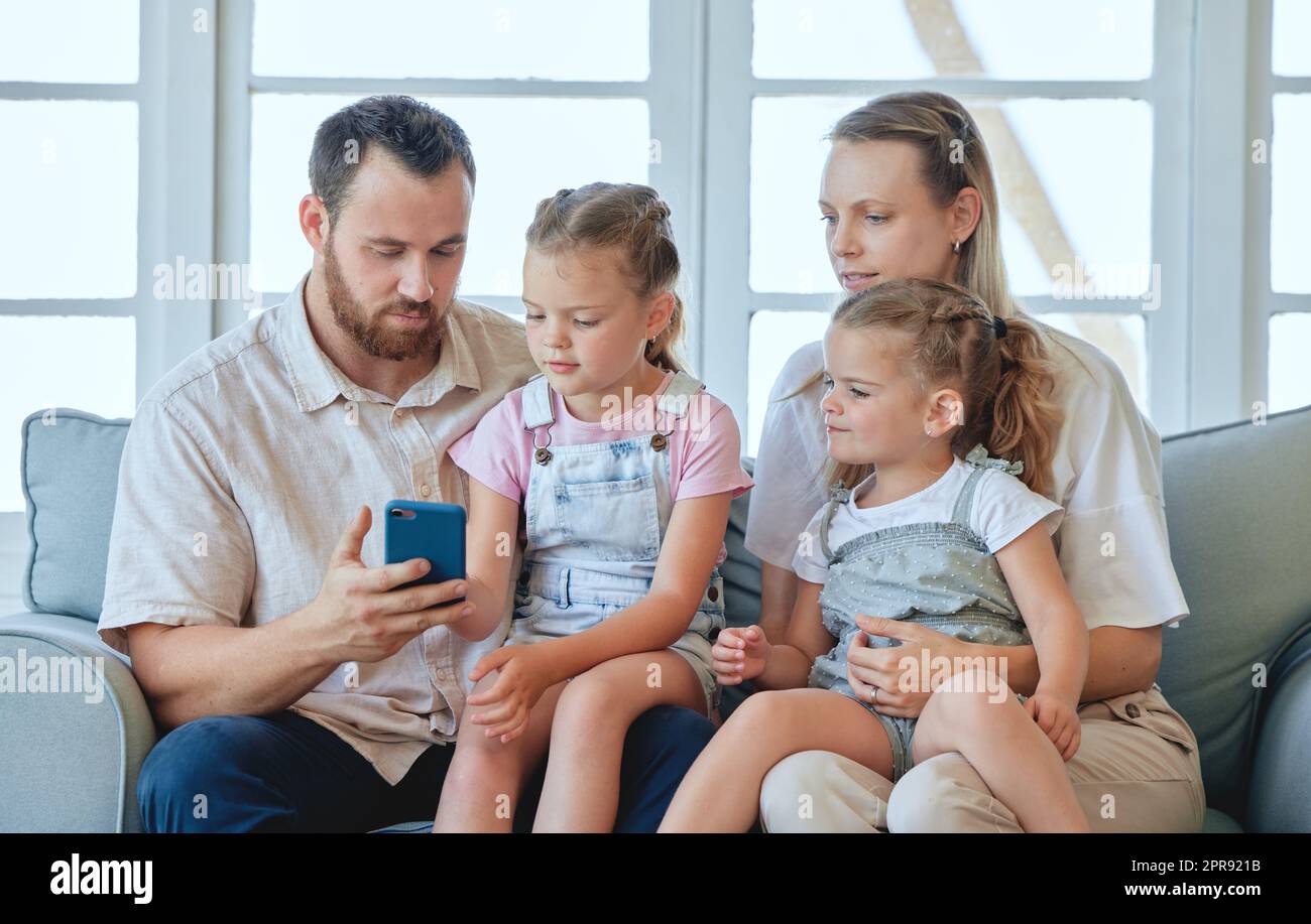 Do you want to send it. a young family using a phone together at home. Stock Photo