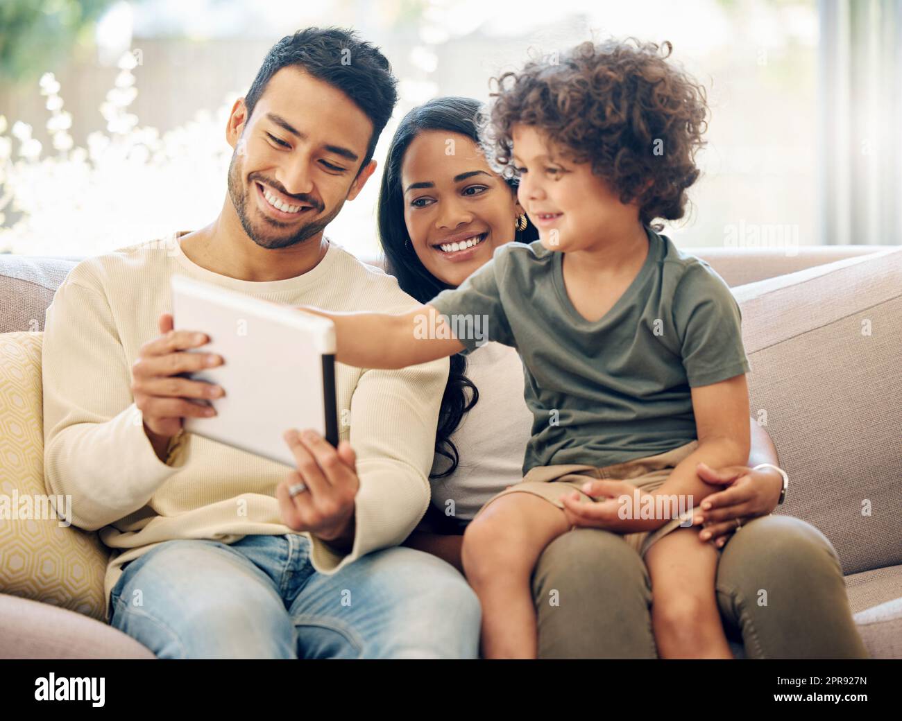 Lets do a little quiz. a little boy using a digital tablet while sitting at home with his parents. Stock Photo