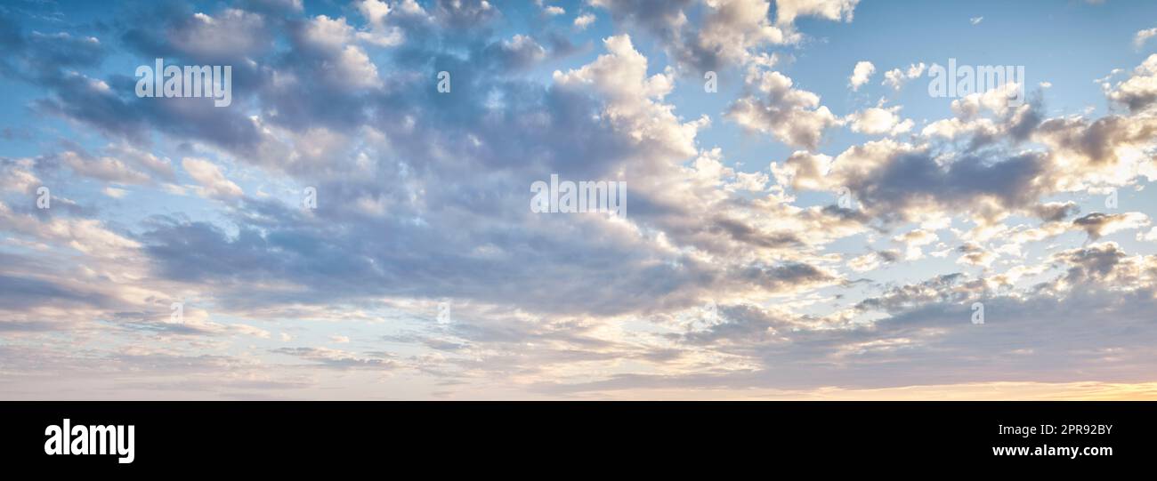 Cumulus clouds in a blue sky from below. Beautiful panoramic of fluffy, puffy and soft white cloudscape background symbolizing spirituality and heaven. Climate and weather in the atmosphere outside Stock Photo