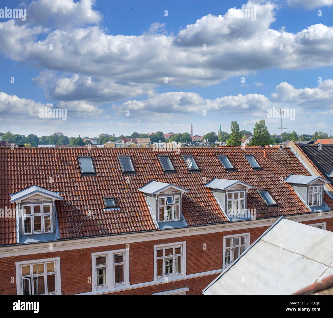 Oldwindow. Rooftop view of buildings in a town with glass windows and frames under a cloudy blue sky. Beautiful landscape architecture with clouds surrounding a suburban urban environment. Stock Photo