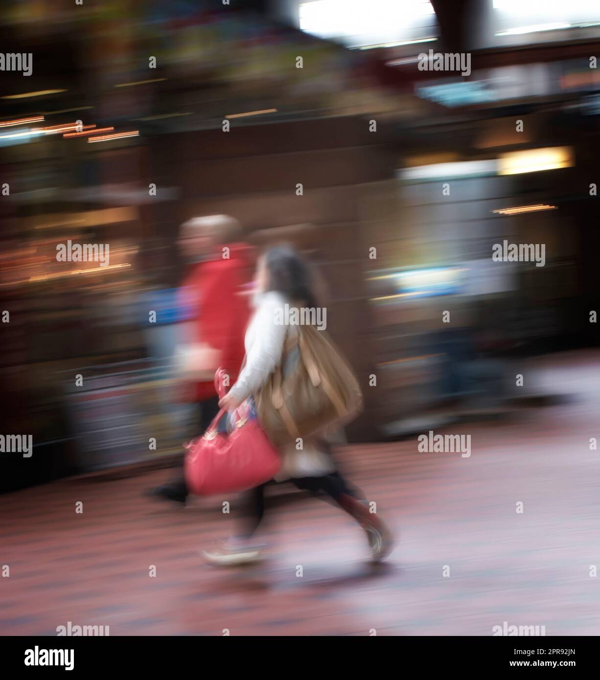 Blurred motion of a couple commuting through an urban town. Man and woman rushing while walking together in a street in the city. Tourists traveling and exploring abroad in defocused movement Stock Photo