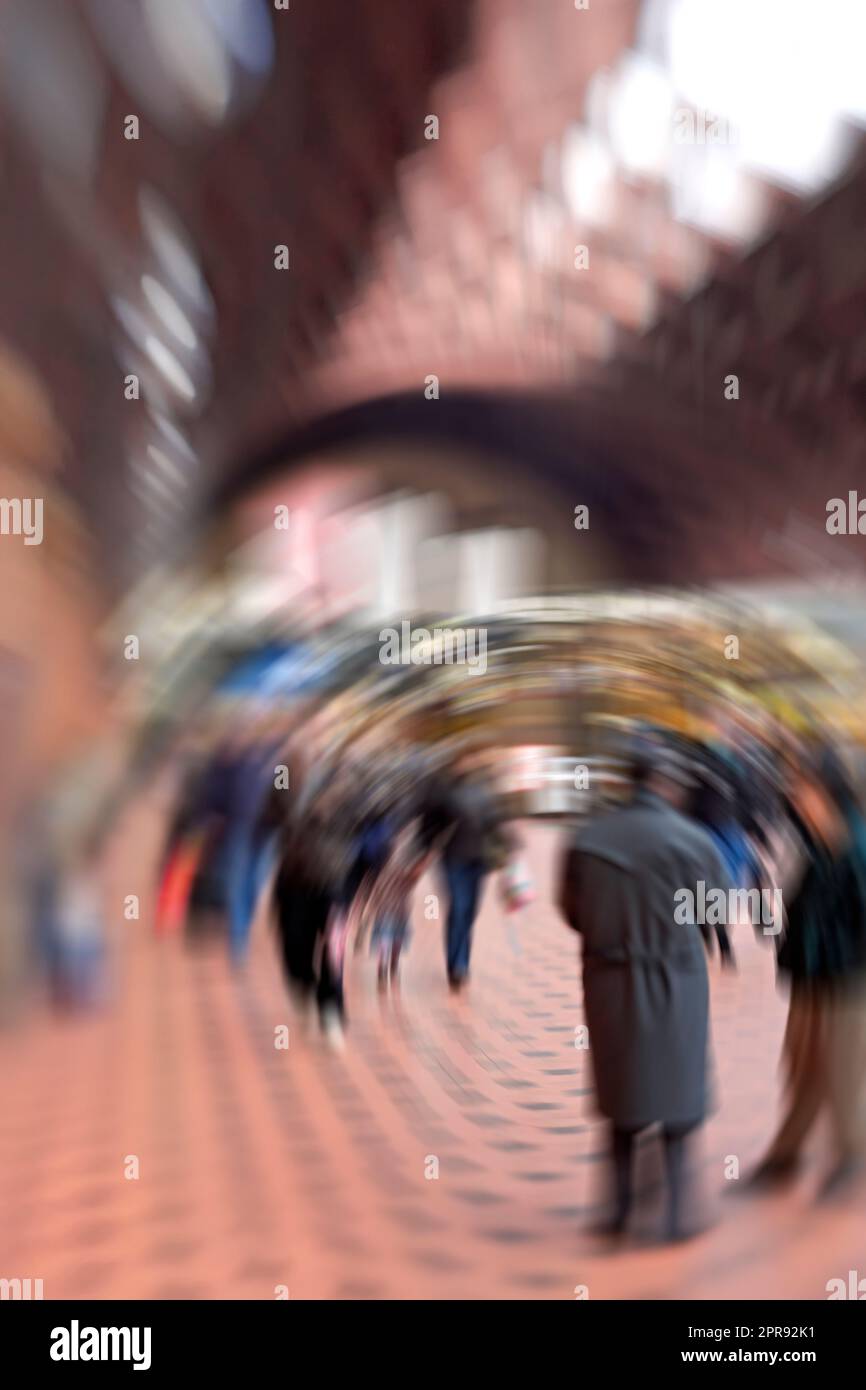 Lens and dizzy motion blur of many people walking at a train station or subway with copy space and bokeh. A blurry crowd of travelers moving along a platform, arriving and departing from busy station Stock Photo