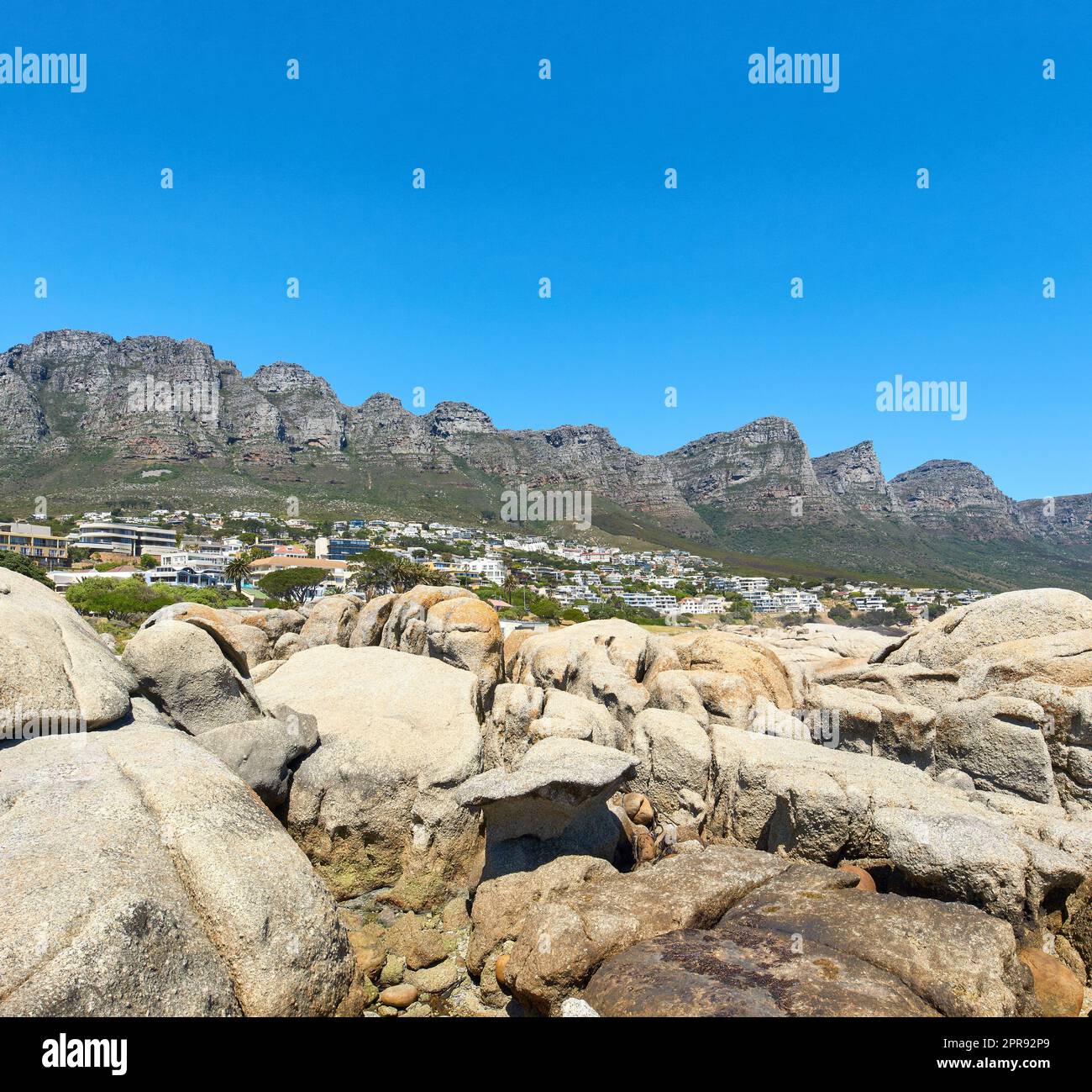 Twelve Apostles at Table Mountain in Cape Town against a clear blue sky background on a sunny day with copy space. View of a peaceful suburb surrounded by scenic mountain landscape and beach boulders Stock Photo