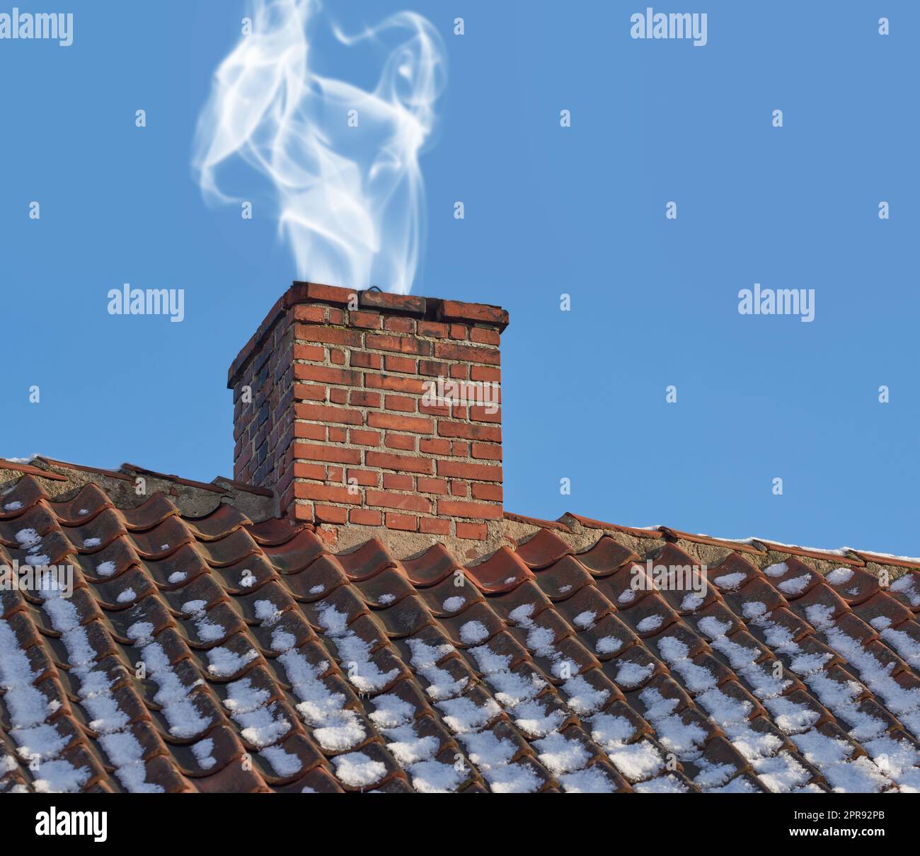 Landscape of chimney blowing smoke on house rooftop exterior design in Denmark during winter. Close up of old architecture redbrick air vent for removing heat and smoke from fireplace with blue sky Stock Photo