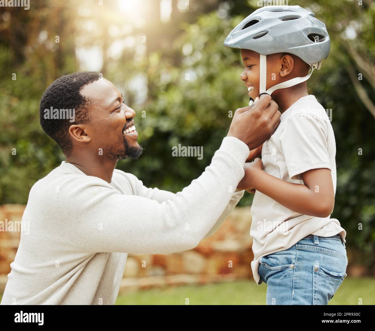 Protecting his baby. a father adjusting his sons helmet outside. Stock Photo