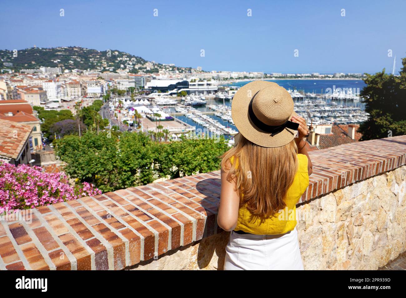 Visiting French Riviera. Back view of pretty girl enjoying ciyscape of Cannes, France. Stock Photo