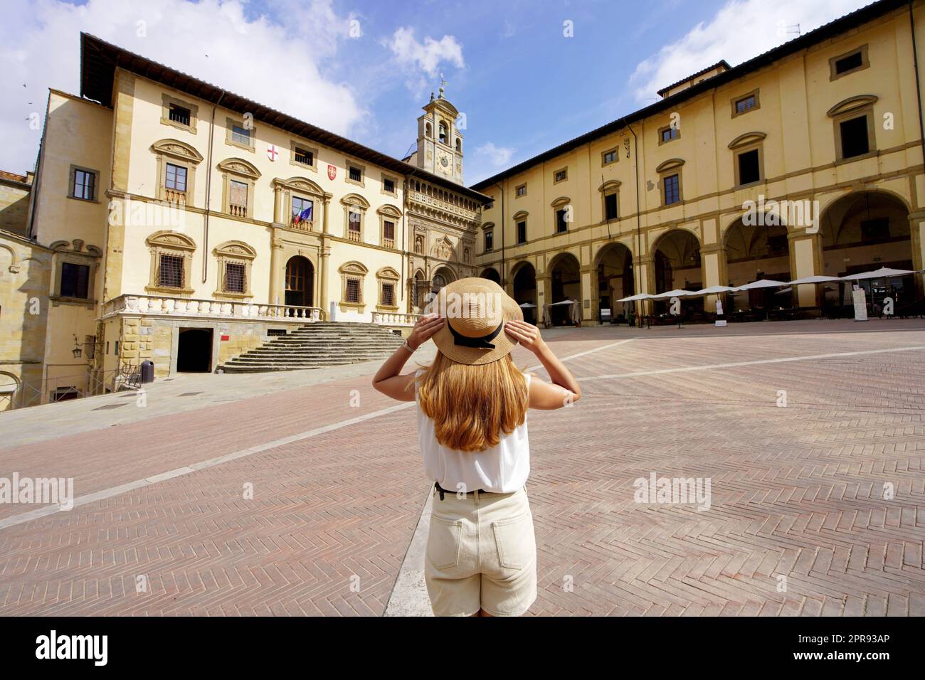 Traveling in Tuscany. Back view of tourist girl holding hat in