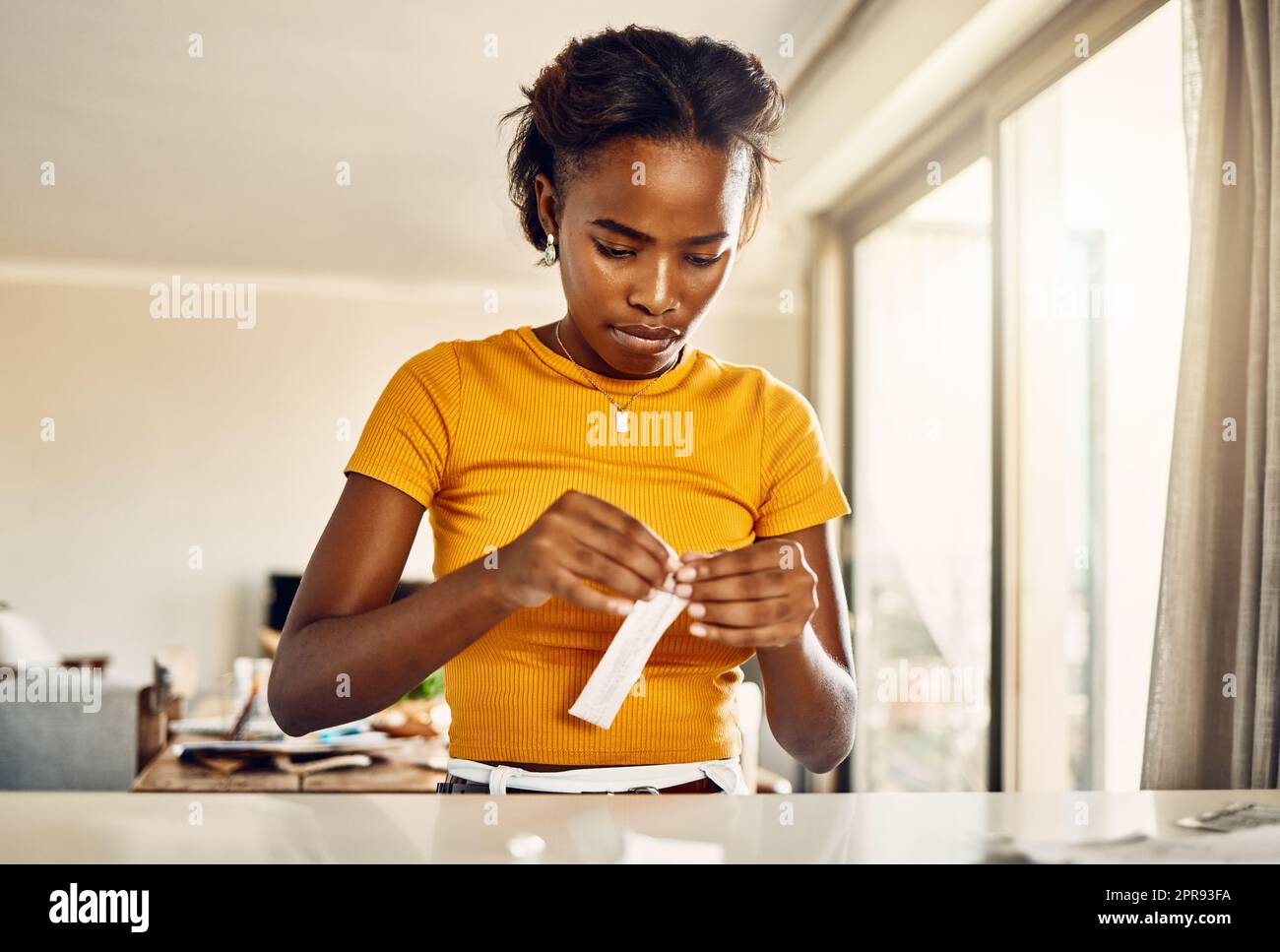 Testing for covid or coronavirus with a rapid antigen test kit at home. African young woman opening a screening kit to diagnose a virus or infection during the pandemic from her house Stock Photo