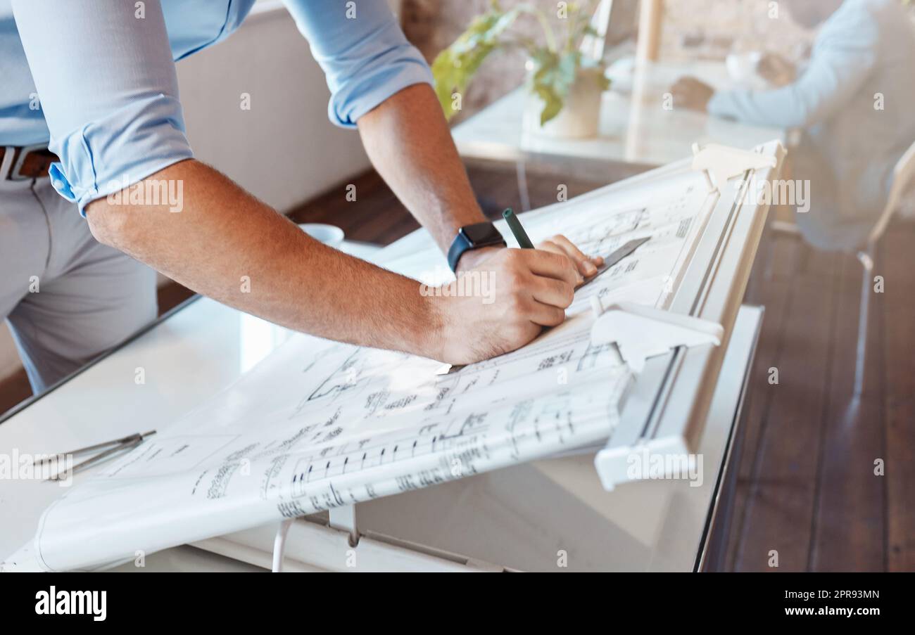 Architect drawing a plan for a building project inside his office. Closeup of a male engineer doing a blueprint sketch at an architecture company or his workplace. Housing planner making a diagram Stock Photo