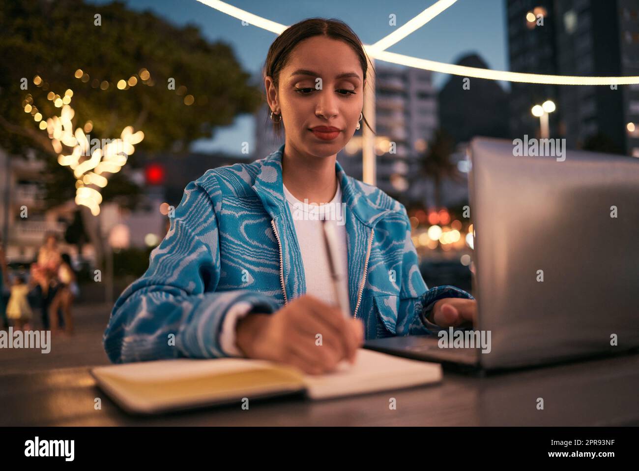 Trendy, creative and smart student studying online with a laptop late at night at a modern campus. Young, inspired and motivated female writer or college academic writing and planning study schedule Stock Photo