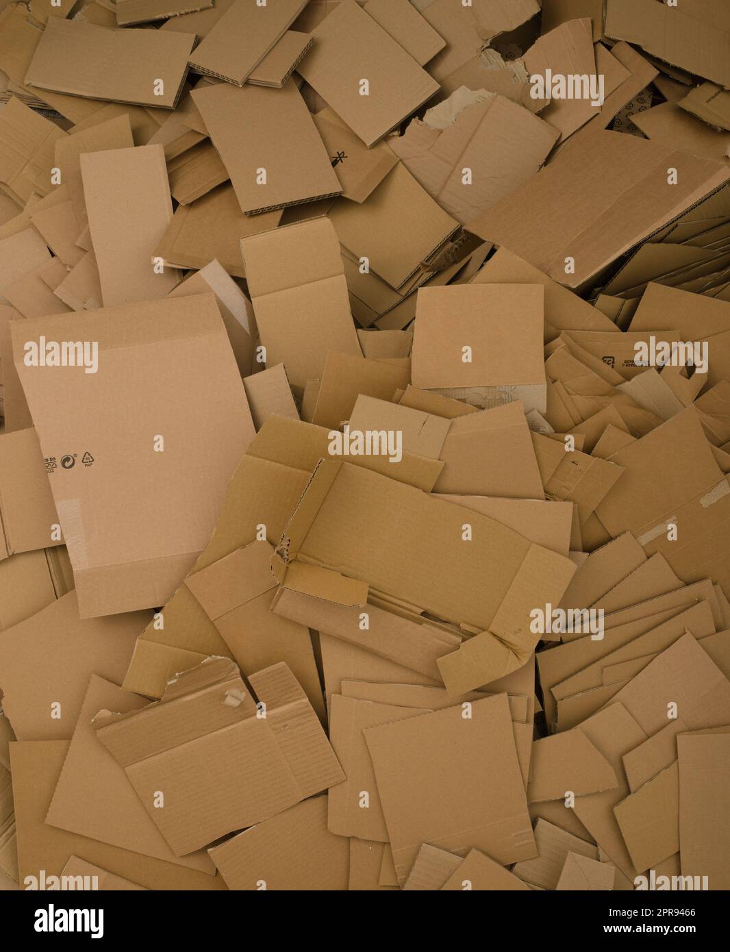 A lot of cut cardboard lying in a large pile. Photo shows the amount of the waste generated by the cardboard packaging. Stock Photo