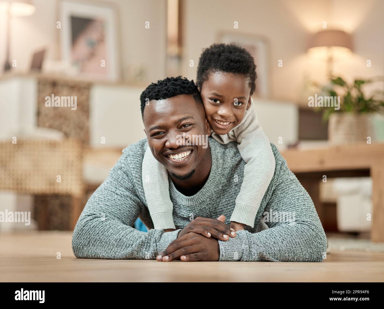 Its about being there for your kids. Full length portrait of a handsome young man and his son lying on the living room floor at home. Stock Photo