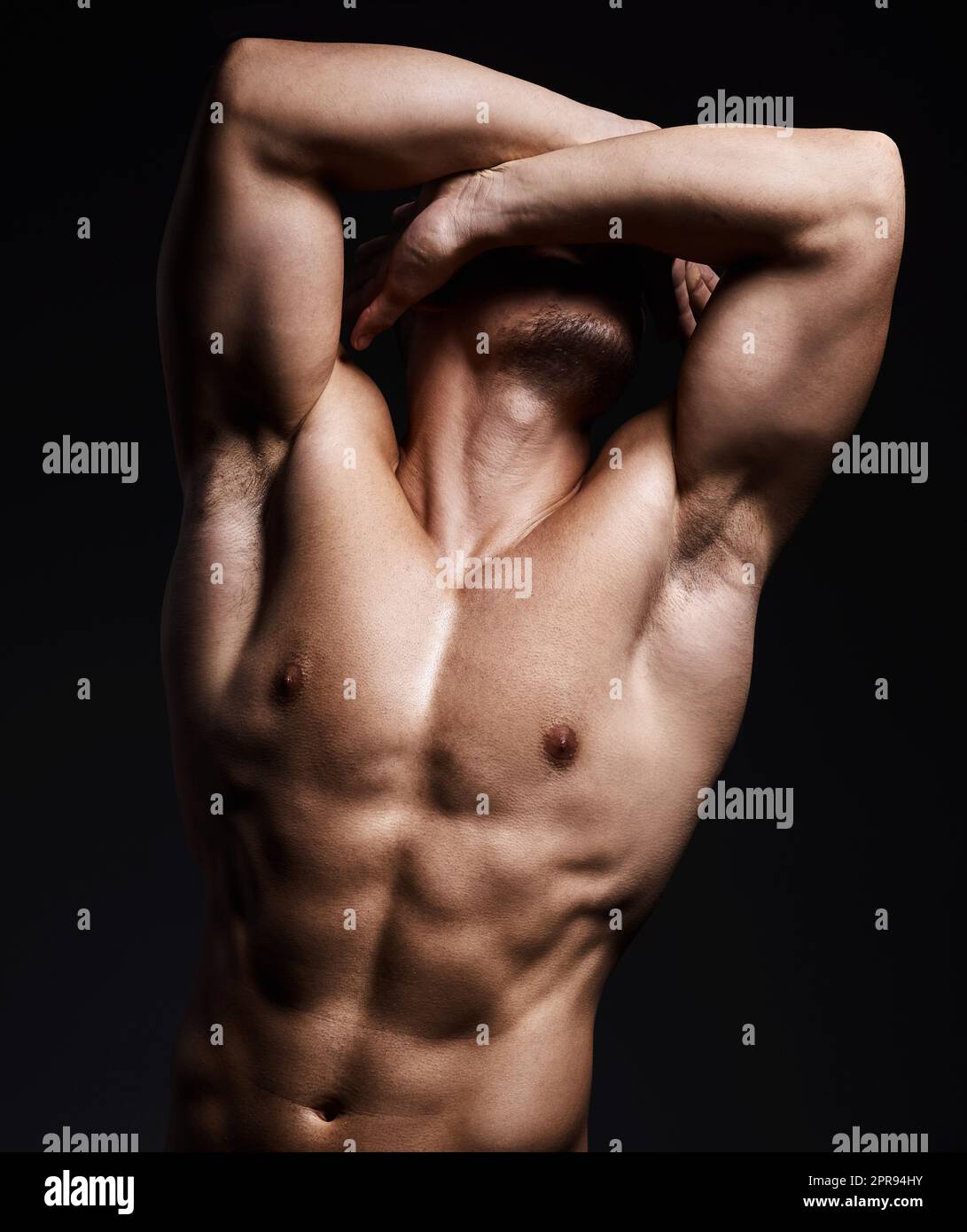Hit the gym and do it hard. a muscular young man posing against a black background. Stock Photo