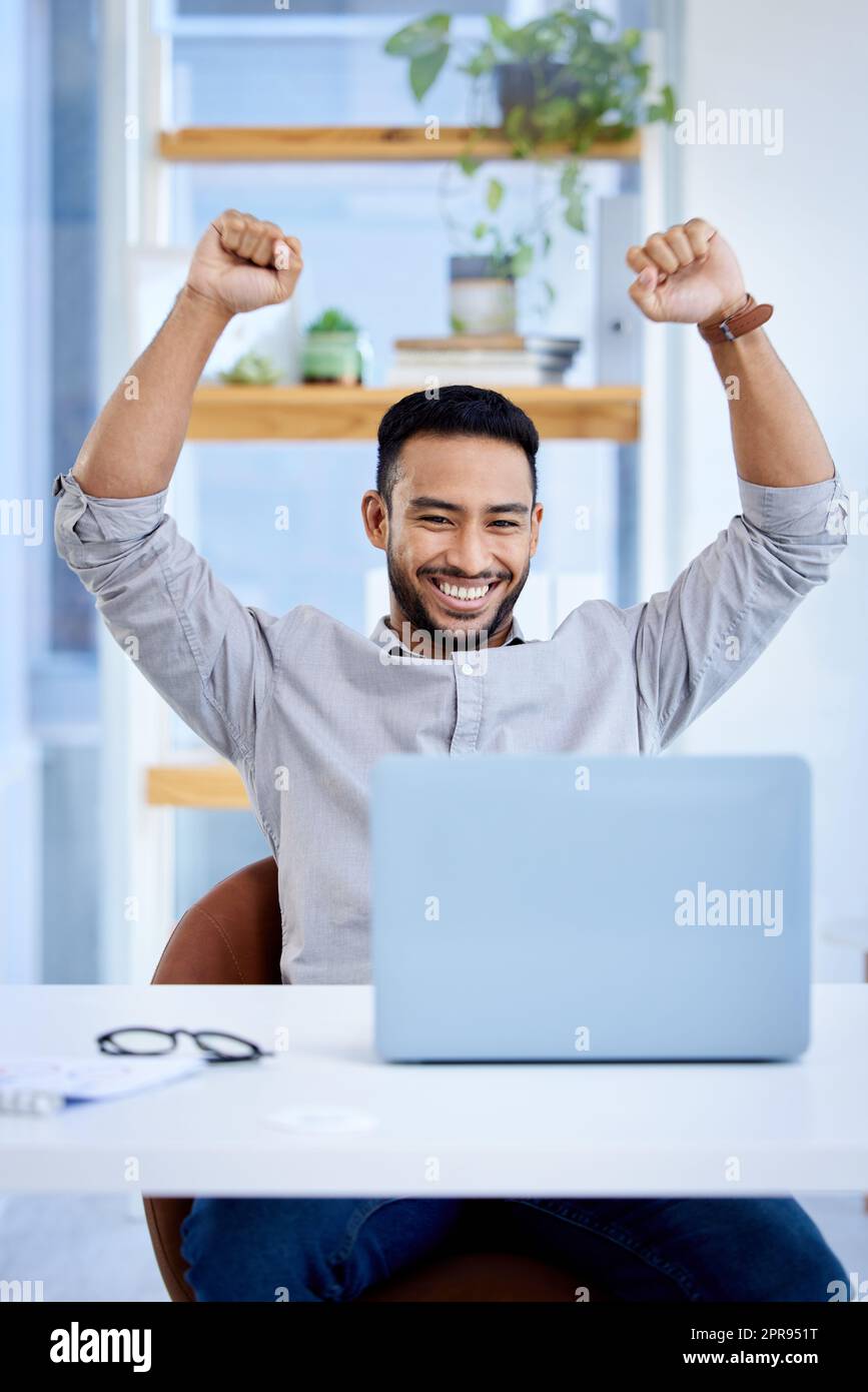 I pushed hard and finally reached my goal. a young businessman cheering while working on a laptop in an office. Stock Photo