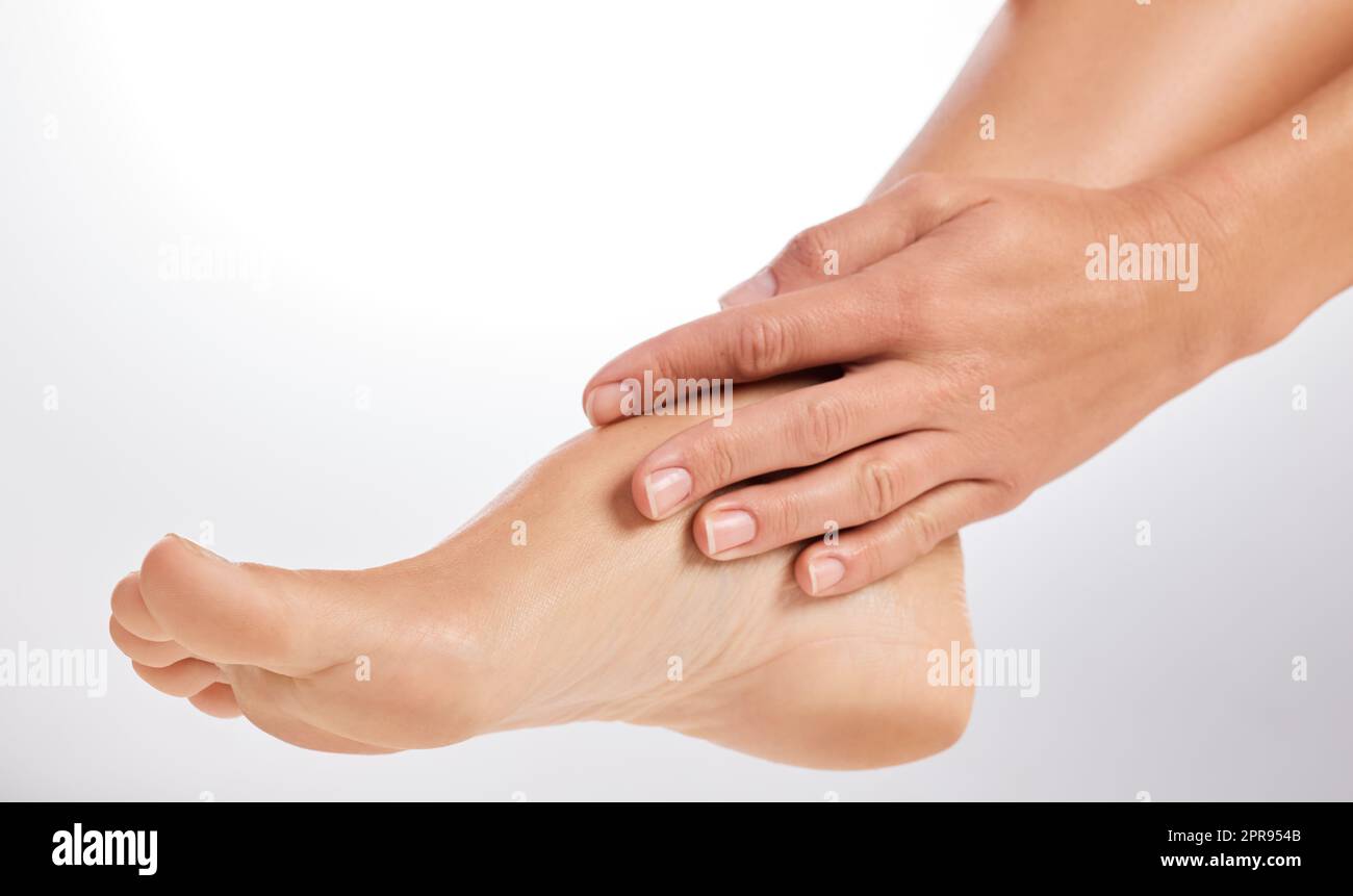 Take care of the feet that carry you through life. an unrecognizable woman touching her foot in the studio. Stock Photo