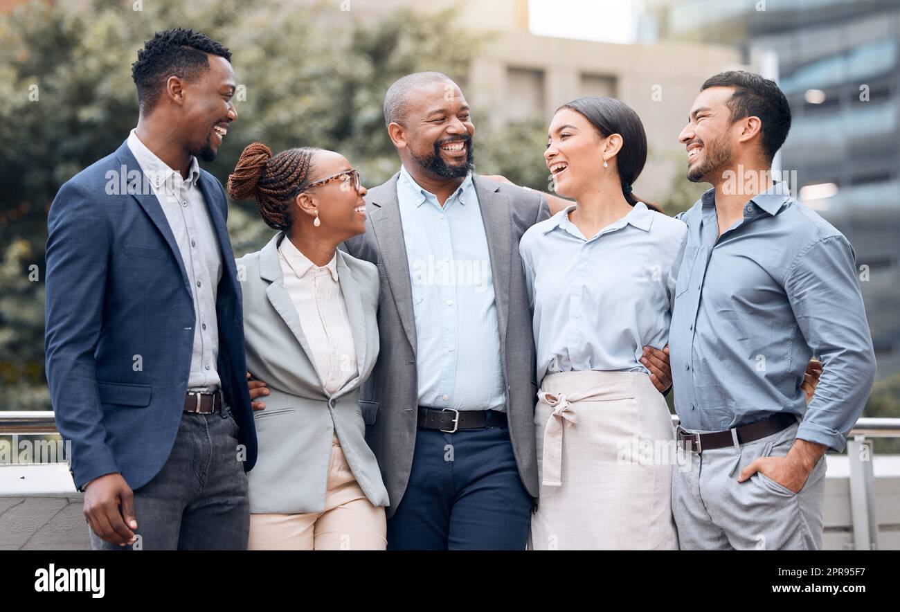 You always make me laugh. a group of businesspeople standing outside together. Stock Photo