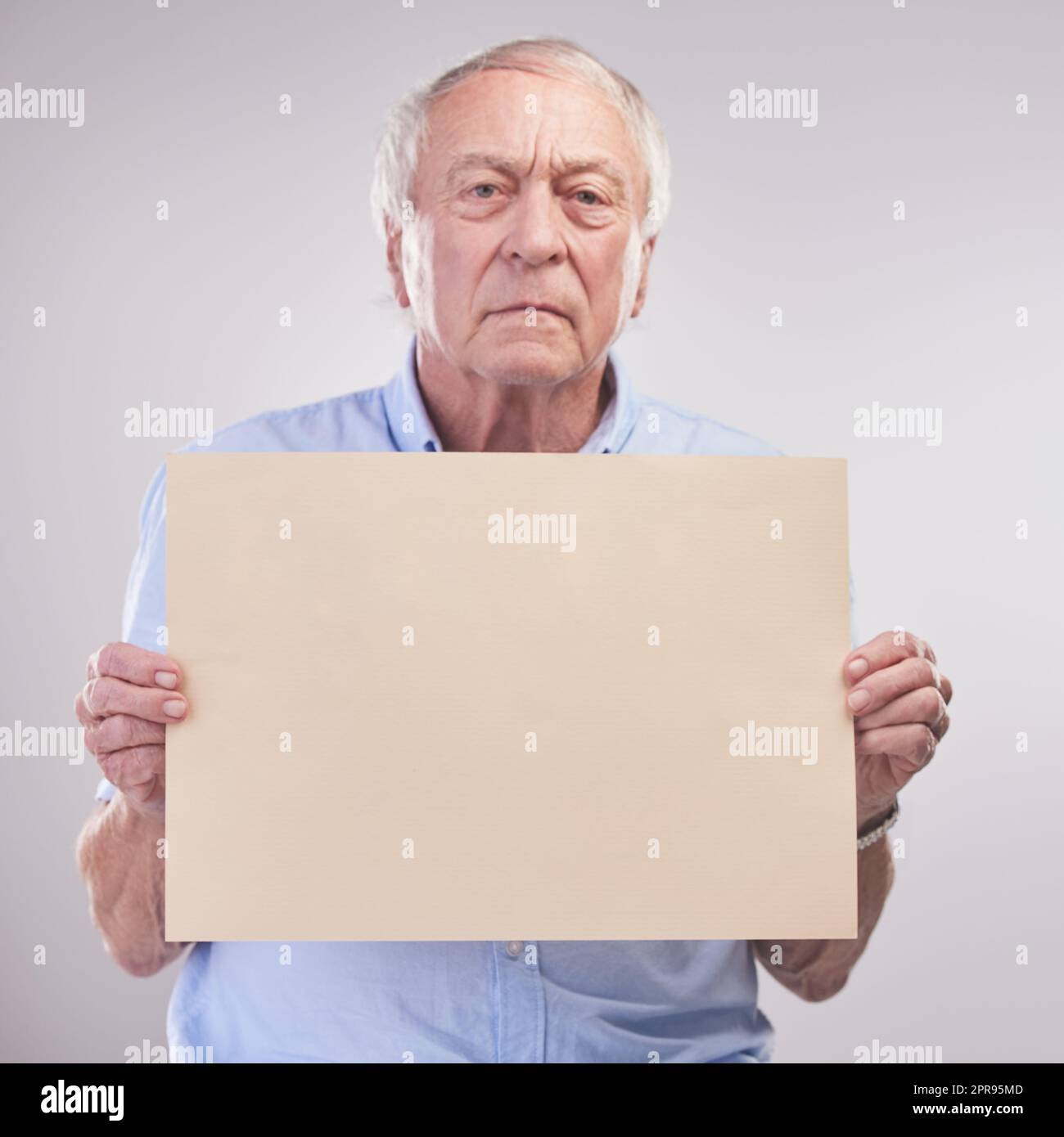 Listen up folks... Studio shot of a senior man holding a blank sign against a grey background. Stock Photo
