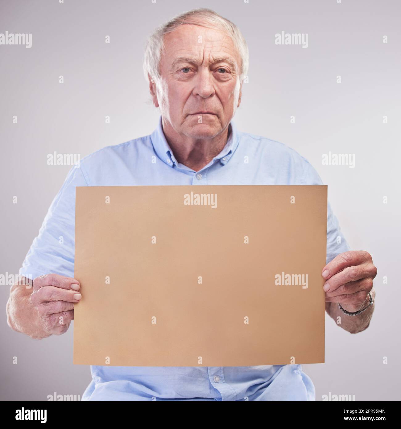 This is as serious as it gets. Studio shot of a senior man holding a blank sign against a grey background. Stock Photo