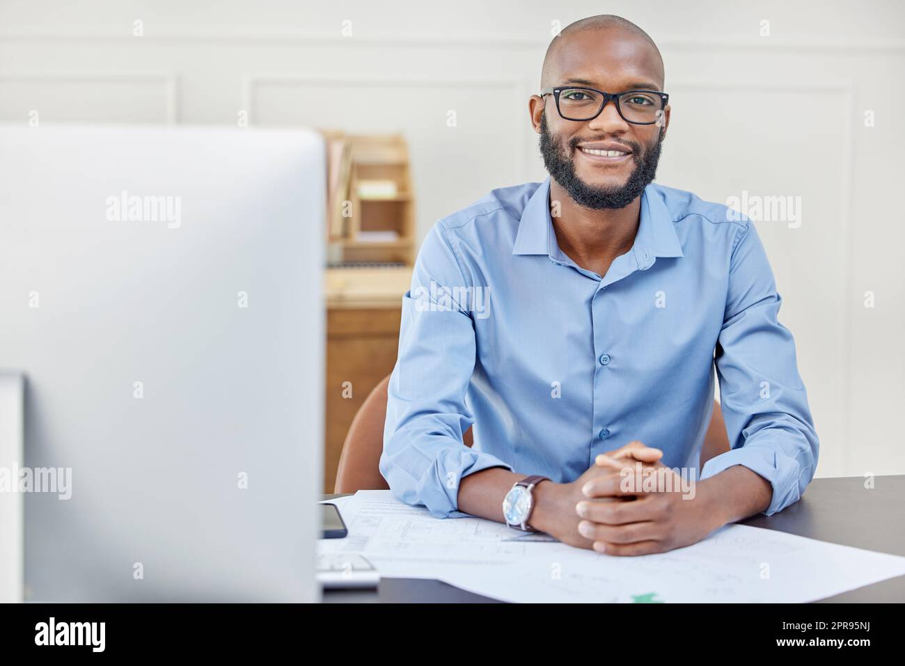 Even when youve reached your goals, keep pushing just as hard. Portrait of a businessman smiling while sitting at his desk. Stock Photo