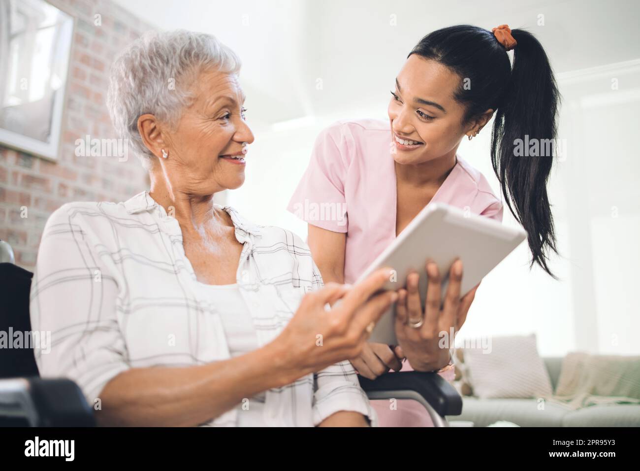 Patience is timeless. a young nurse sharing information from her digital tablet with an older woman in a wheelchair. Stock Photo