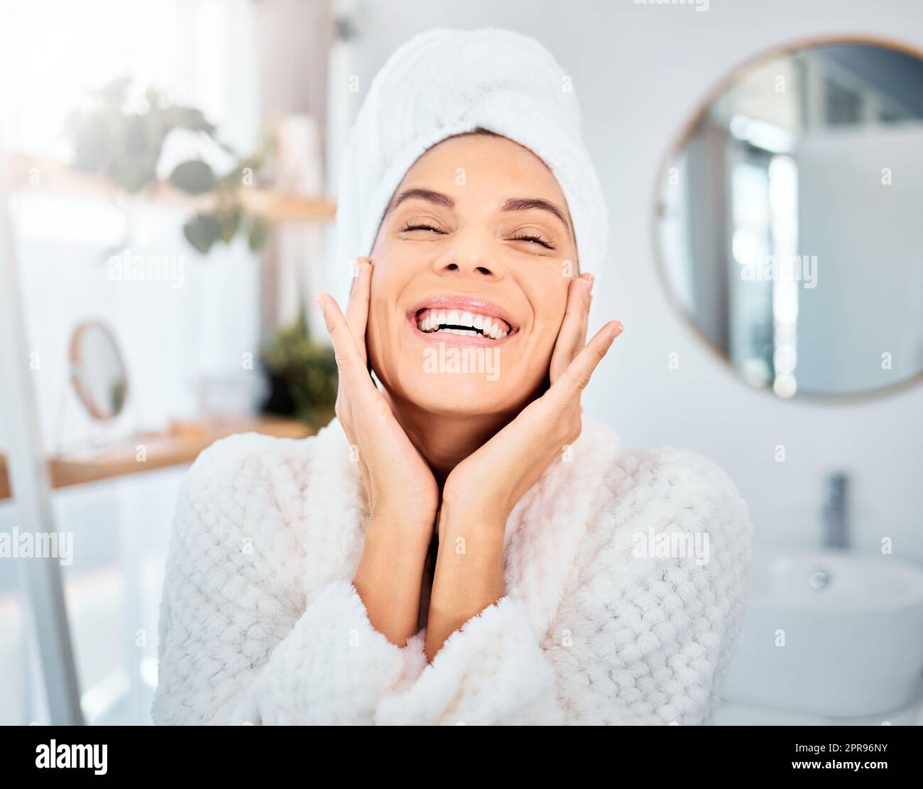 Feeling joy from the inside out. a young woman applying moisturiser to her skin in her bathroom. Stock Photo