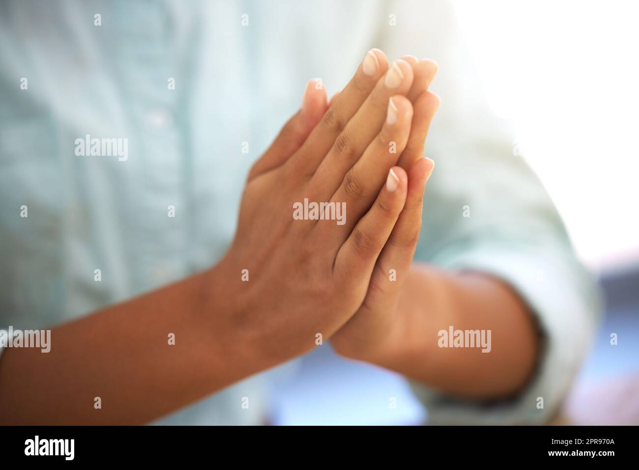 Start your day off with a prayer. an unrecognizable person sitting with their hands together. Stock Photo