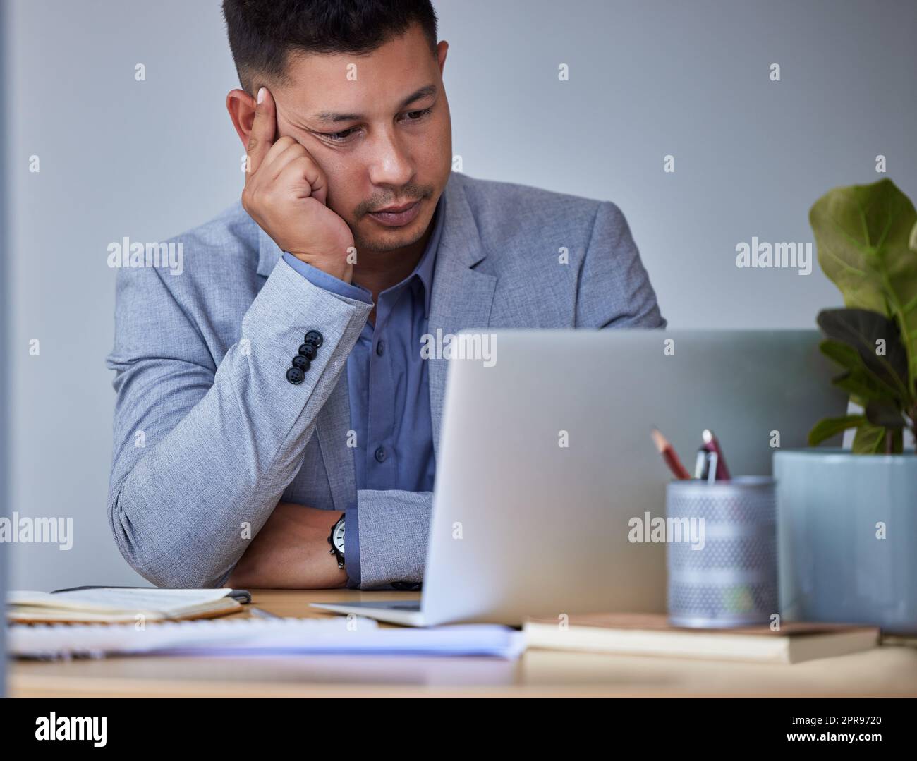 I need a vacation. a young businessman looking bored at work. Stock Photo