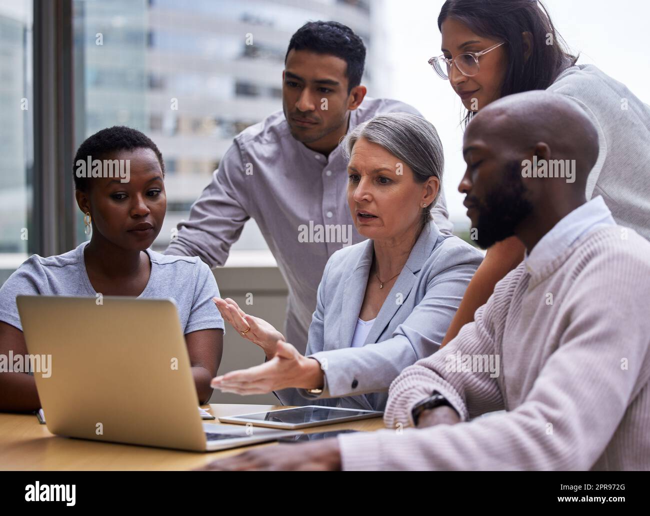 Chase the vision, not the money. a group of professional coworkers using a laptop together at work. Stock Photo