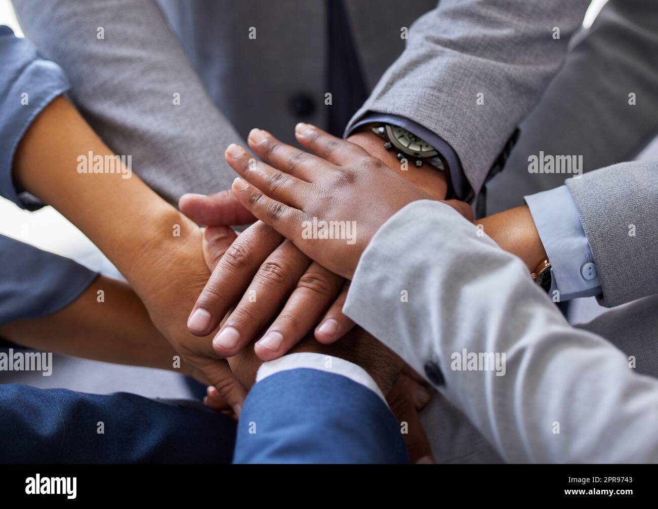 We can do this but only together. a diverse group of businesspeople standing together in the office with their hands piled in the middle. Stock Photo