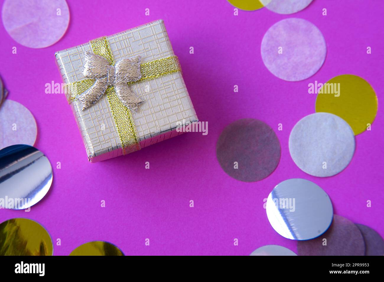 Golden gift box on pink confetti background. Thanksgiving, celebration, romantic. Cheerful and colorful composition to celebrate birthdays or Valentin Stock Photo