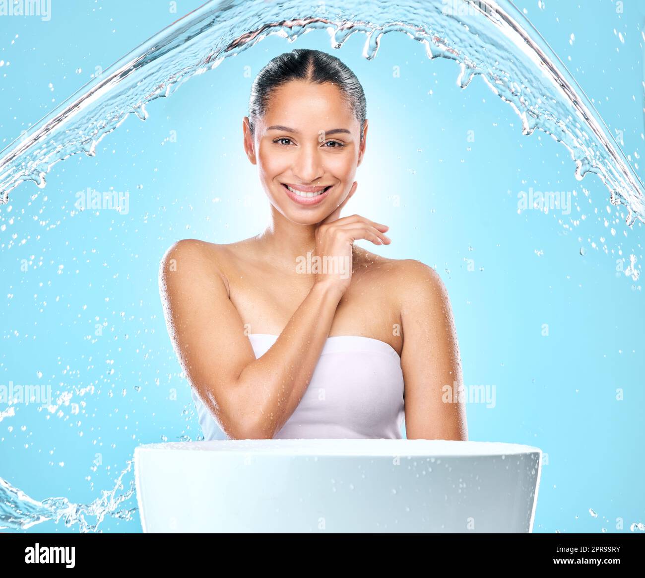 Clean up your act. Studio shot of clean water splashing against a woman. Stock Photo