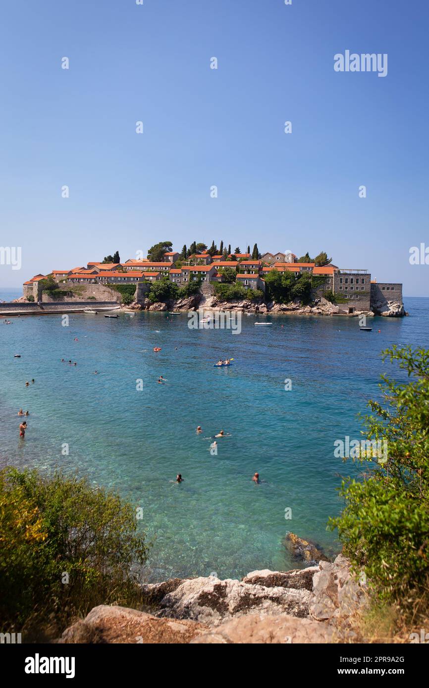 Saint Stephen, Montenegro, 07.07.2021: Famous architectural monument of an island resort in the Adriatic Sea, Montenegro. The concept of recreation at sea, people bathe in the sea. Stock Photo