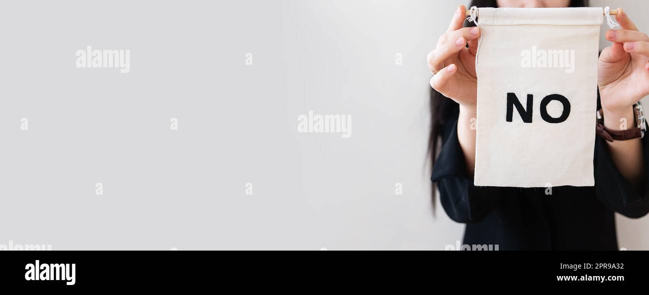 Young business woman in a black suit shows a blank white billboard on a white isolated background. There is no inscription on the poster. Concept for business and advertising. Banner. Stock Photo