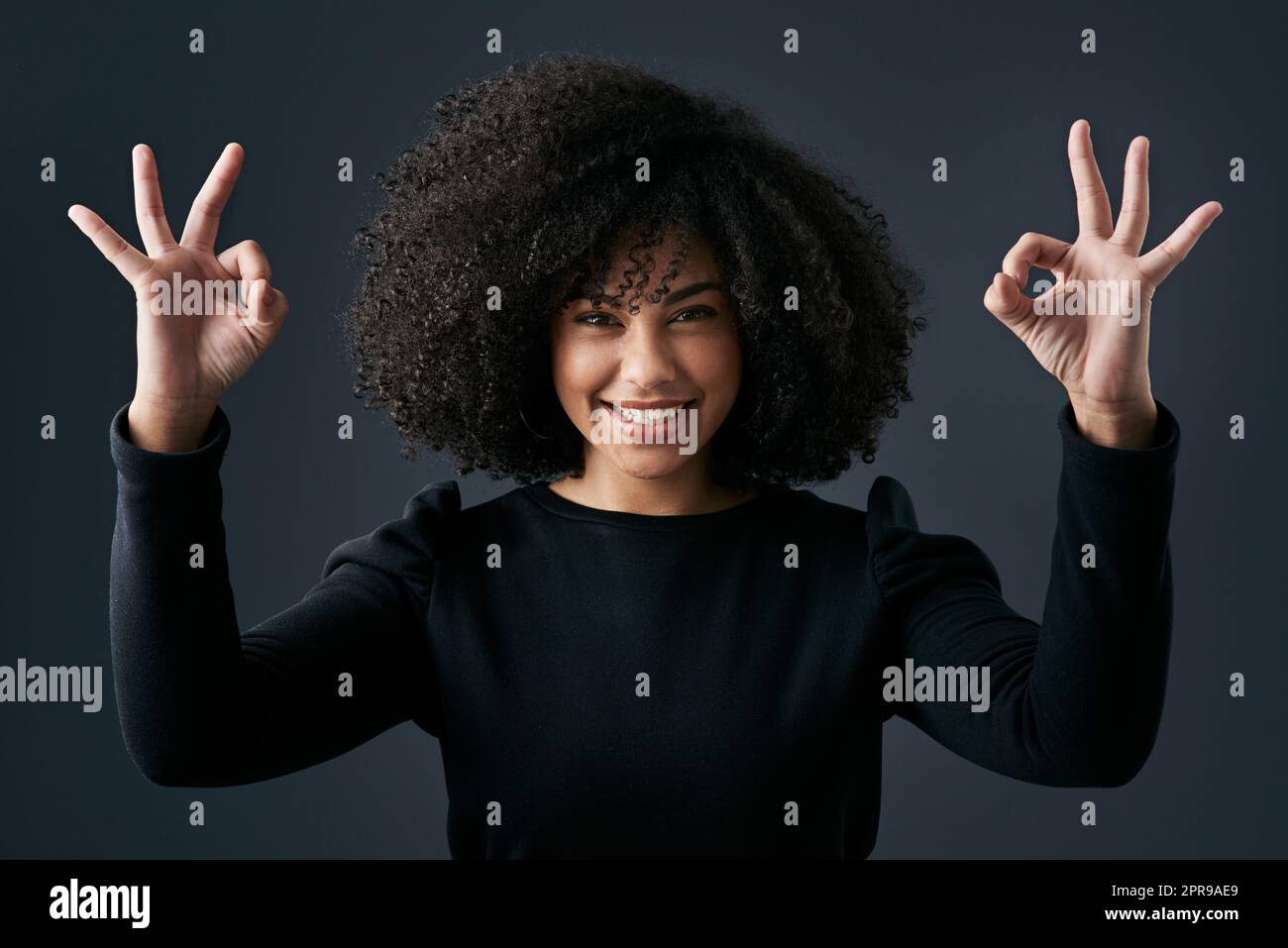 Find your happy place. a young businesswoman making hand gestures against a studio background. Stock Photo