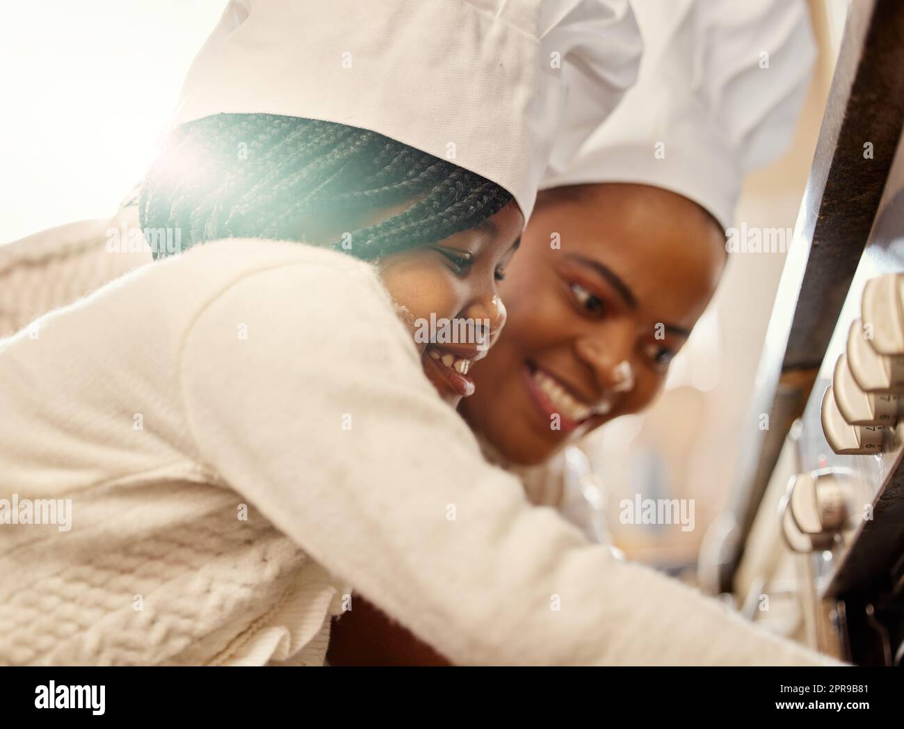 Now we wait until its done. a mother and her daughter baking in the kitchen at home. Stock Photo