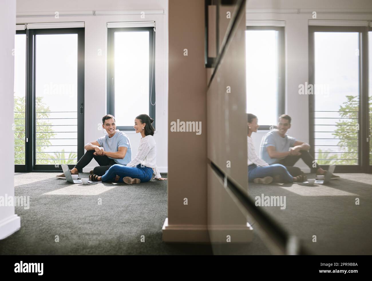 Weve got our work cut out for us. Full length shot of a young couple sitting on the floor together in the new house and using a laptop. Stock Photo