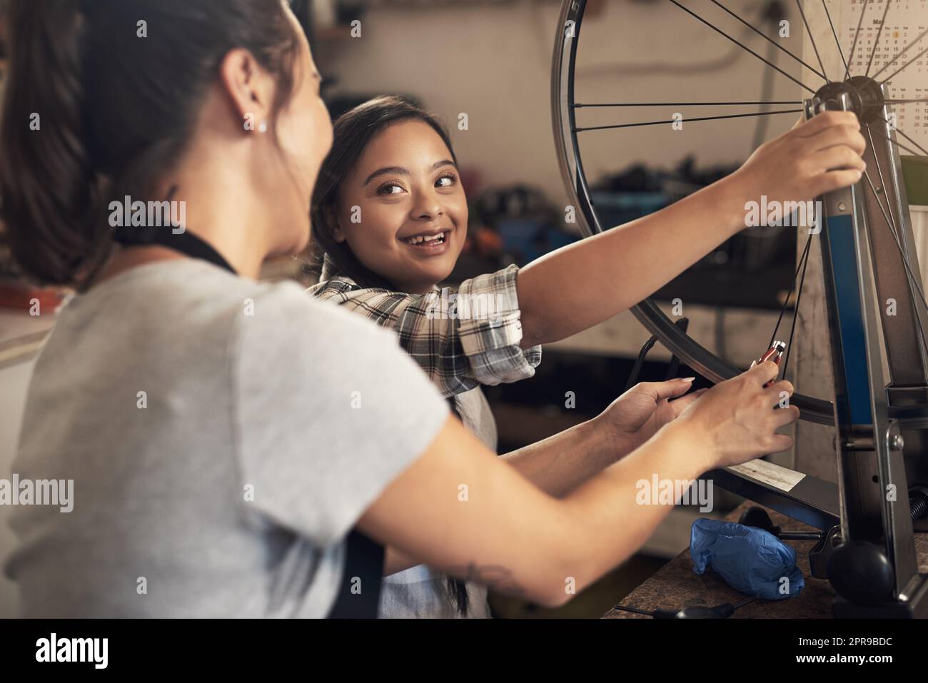A tomboy is the heart of every princess. two young female workers fixing a bike at a bicycle repair shop. Stock Photo