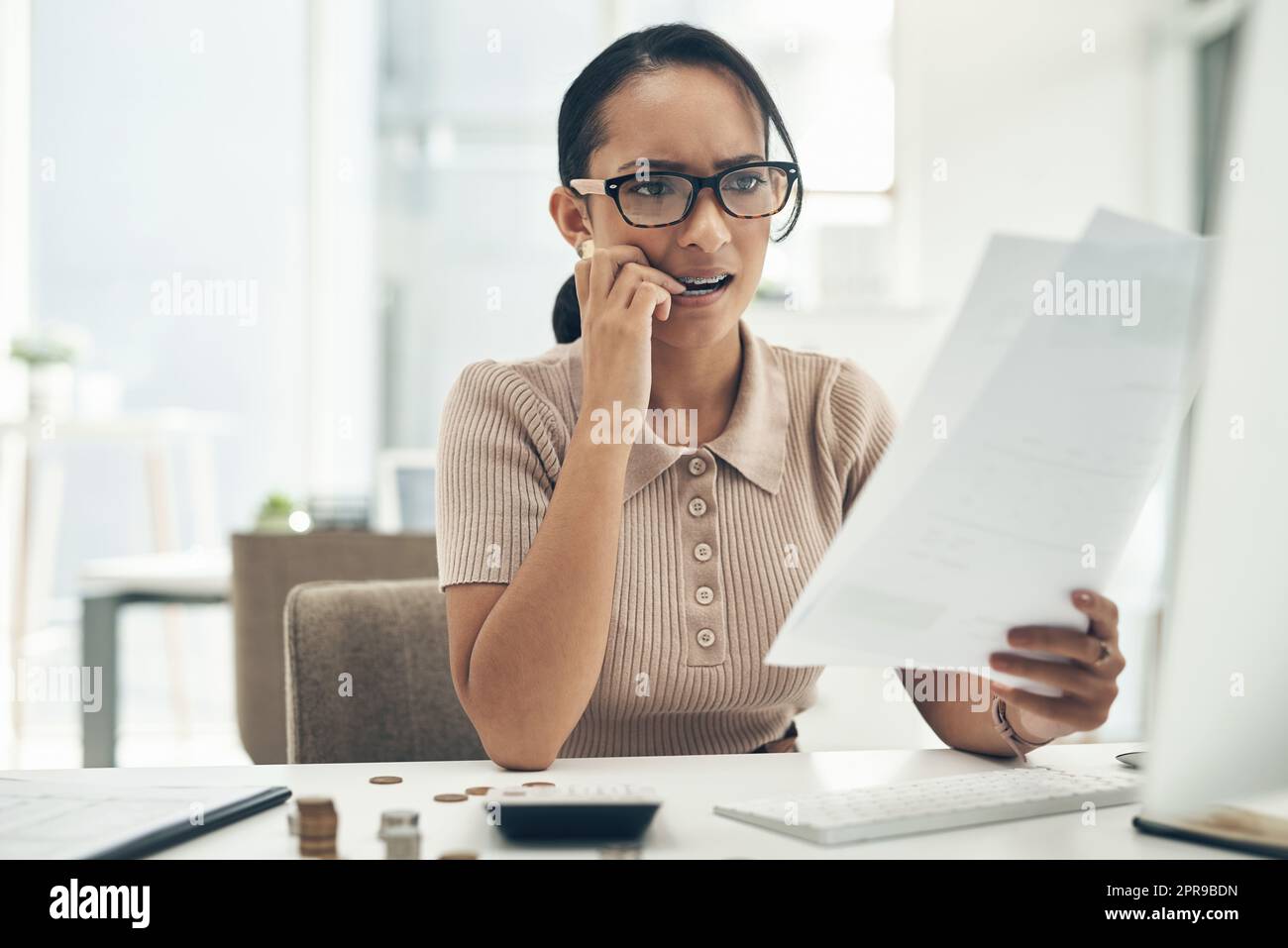 Bad budgeting can lead to more financial stress. a young businesswoman looking stressed out while calculating finances in an office. Stock Photo