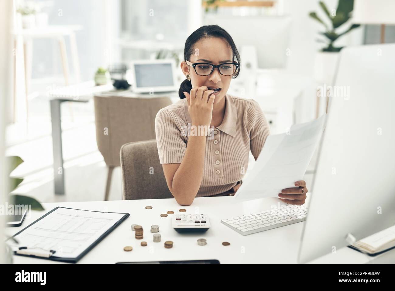 Money matters always stress me out. a young businesswoman looking stressed out while calculating finances in an office. Stock Photo