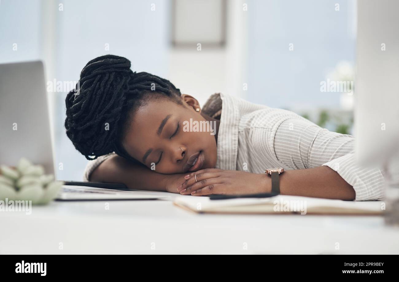 This day has worn me out. a young businesswoman taking a nap on her desk at work. Stock Photo