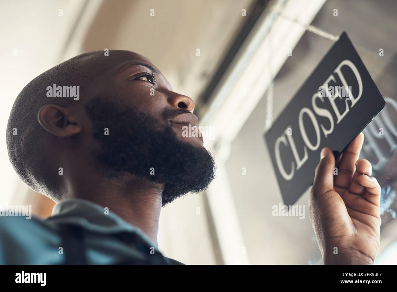 Were open. Low angle shot of a handsome young man standing and turning the sign on the door to his bicycle shop. Stock Photo
