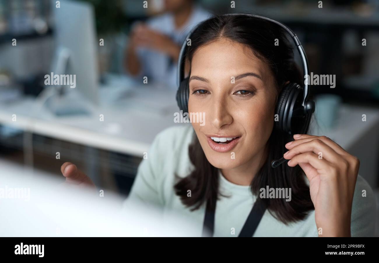Theres no waiting around when shes on the line. a young woman using a headset and computer in a modern office. Stock Photo