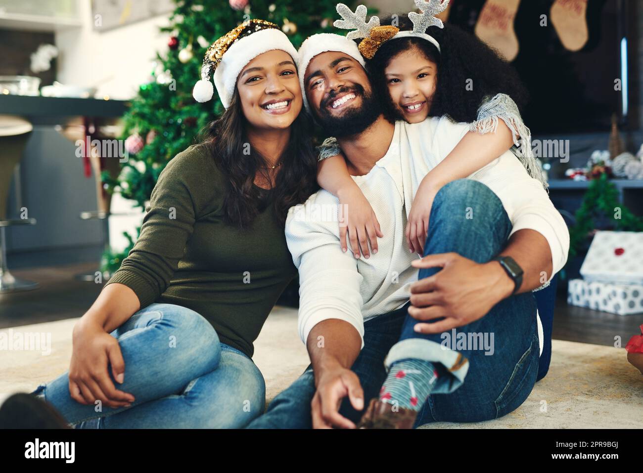 The spirit of Christmas summed up in one moment. Portrait of a happy young family celebrating Christmas at home. Stock Photo