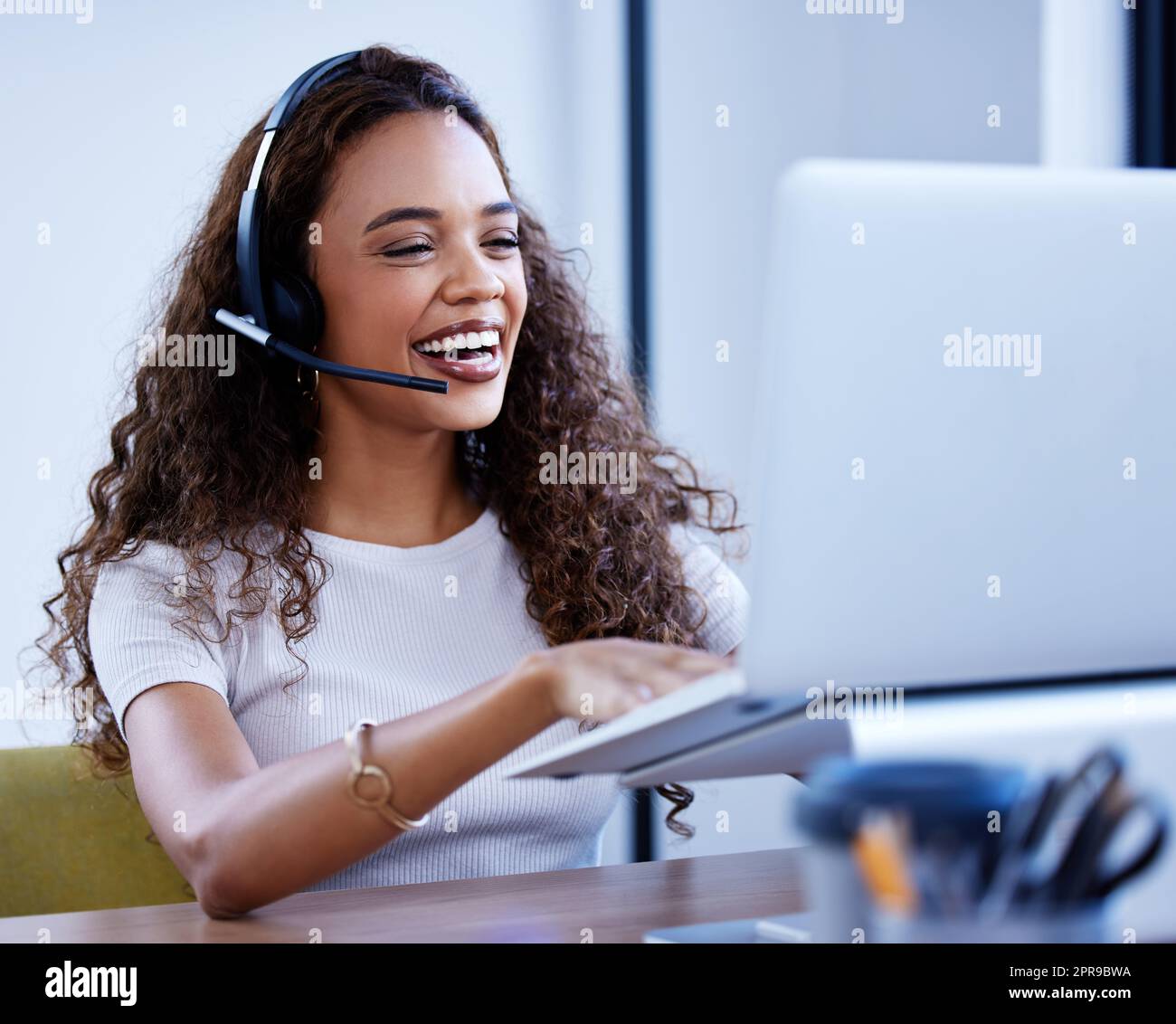 Shes always tops in the sales game. a young call centre agent working on a laptop in an office. Stock Photo