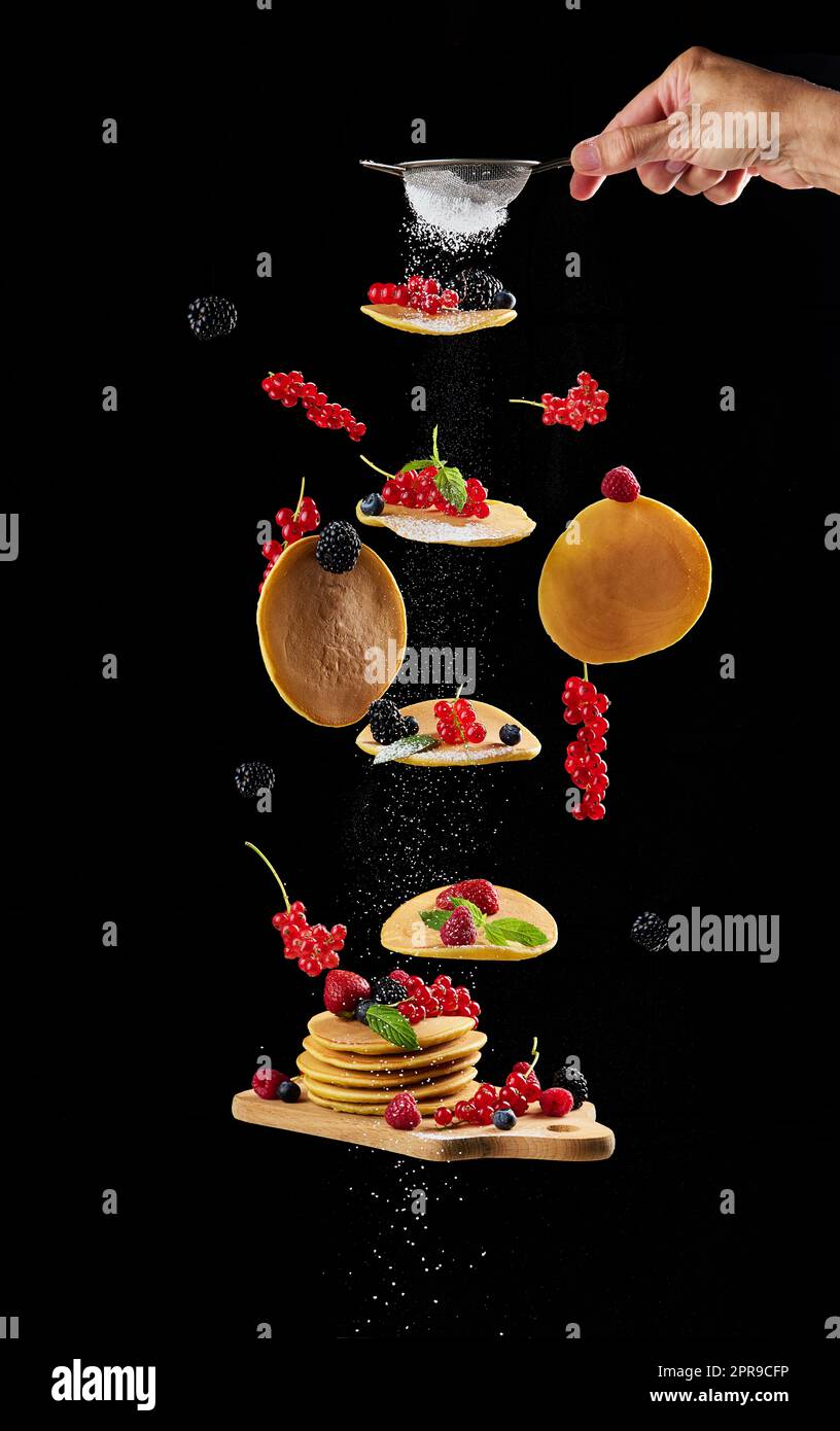 Levitating round pancakes, various fruits on a black background Stock Photo