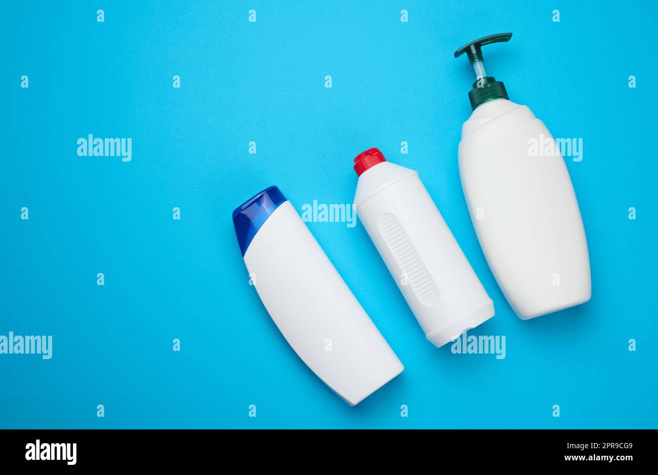 White plastic bottles with a pump for shampoo, shower gel on a blue