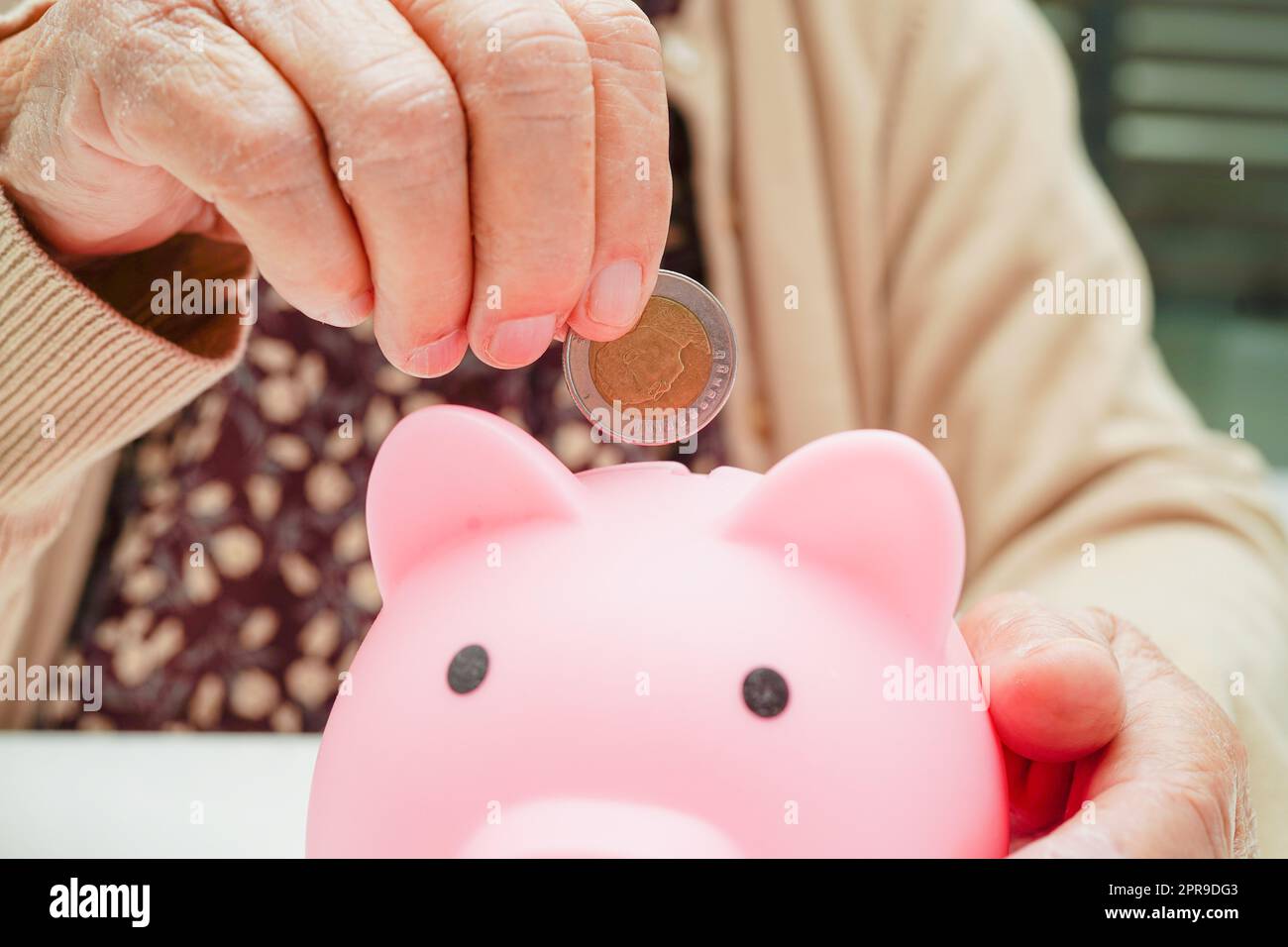 Retired elderly woman putting coins money in piggy bank and worry about ...