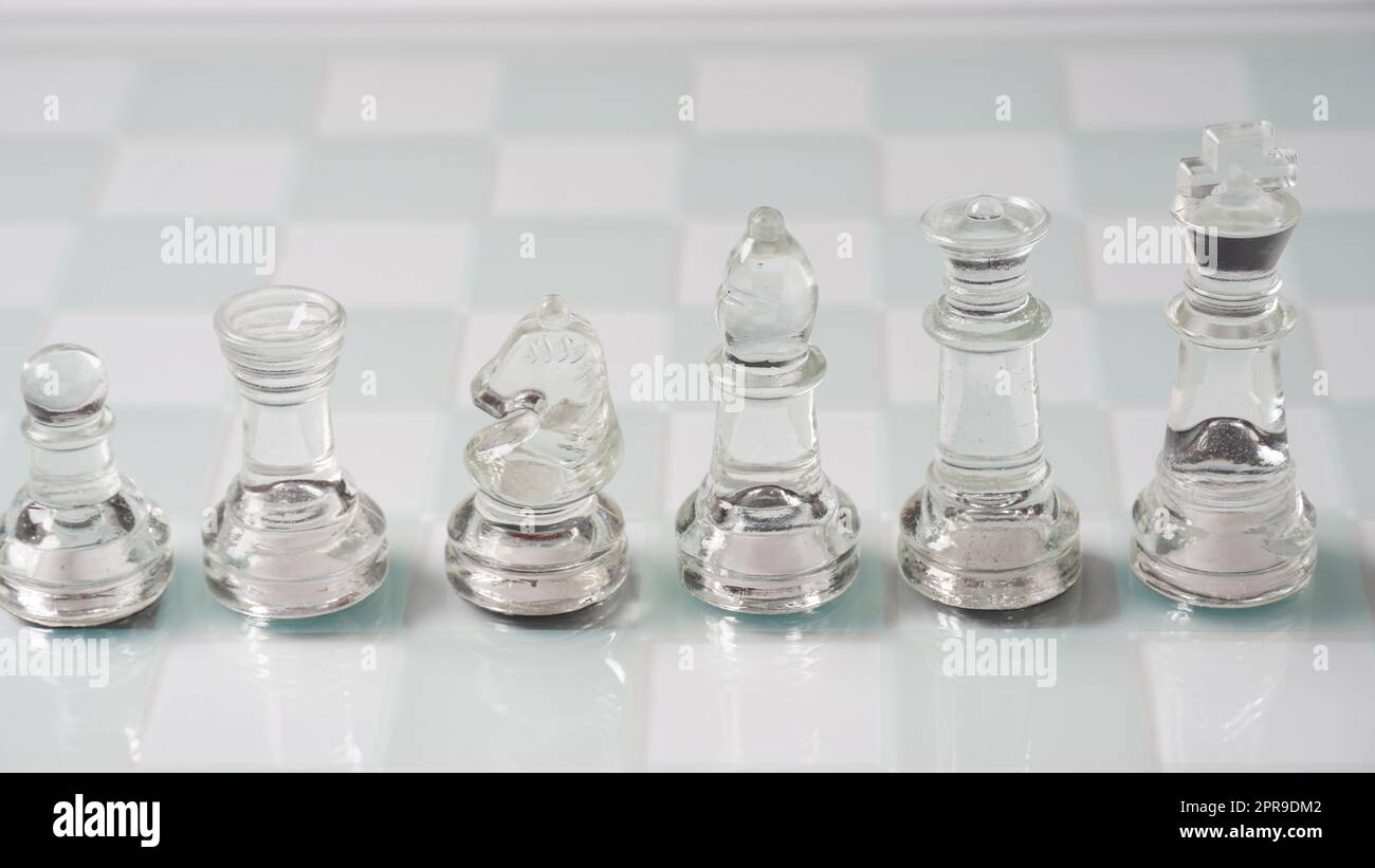 Pieces of transparent chess, King,  Queen, Knight(Horse) , Bishop, Rook, Pawn . Transparent chess figures on chessboard. Stock Photo