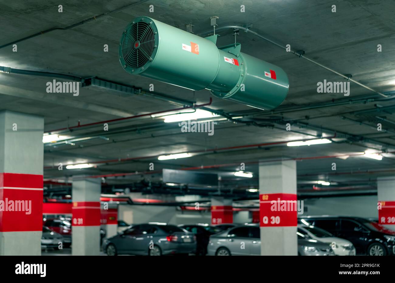 Jet fan at underground parking area. Ventilation fan in the parking lot. Air flow system. Ventilation system in underground car parking lot at commercial building. Duct fan air ventilation at mall. Stock Photo