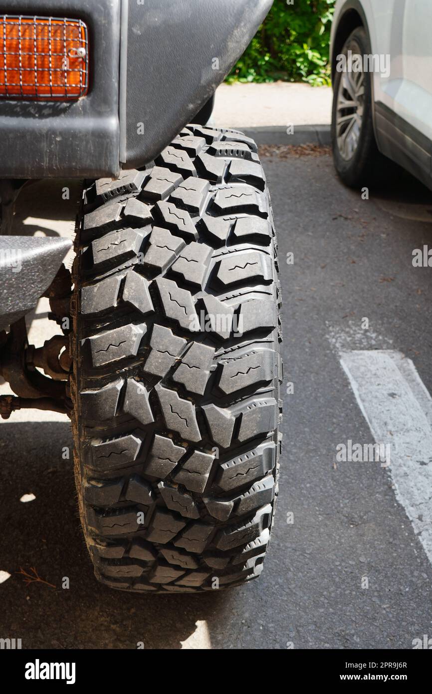 Closeup of strong indented texture of front tire of four-wheel-drive car parked on asphalt in the city Stock Photo